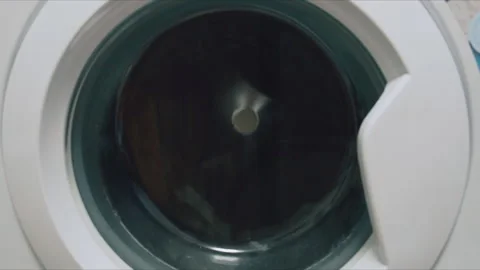 Close up of clothes tumbling in a white washing machine during spin cycle at 库存影片 345080346