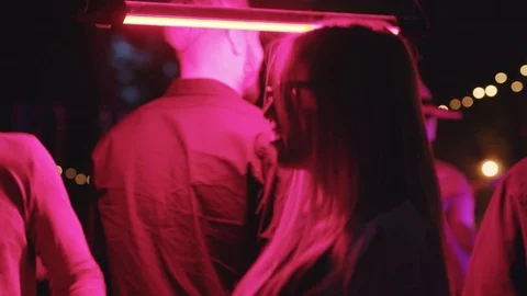 Close-up into a club crowd dancing in neon lights at night party. Flythrough Stock Footage 115358765