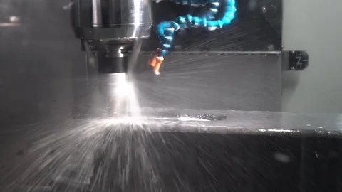 Close-up cnc machine milling a metal part with coolant and flying splashes Stock Footage 119985340