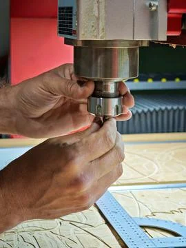 Close up of CNC router operator hands changing drill bit on spindle Stock Photos