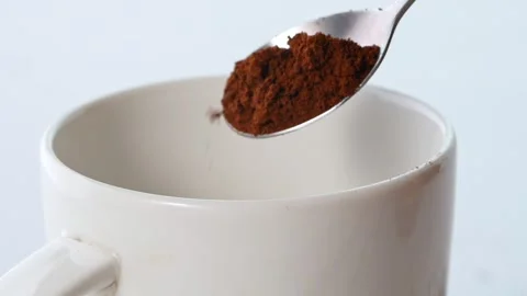 Close up of cocoa powder falling from a spoon into a white cup Stock Footage 160812867