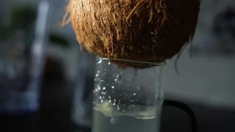 Close-up of a coconut dripping fresh liquid into a glass on a dark backgrou.. Video stock 339022602