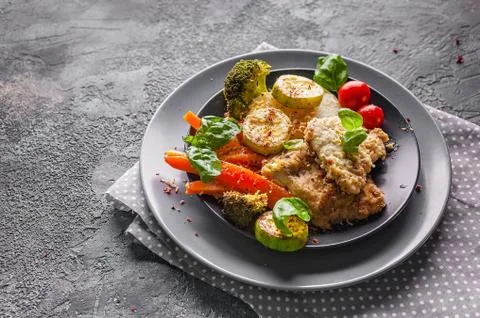 Close-up cod with baked vegetables and fresh basil. Healthy and tasty food. T Stock Photos
