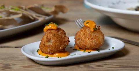Close-up of cod fritters served as tapas on plate on a wooden table. Stock Photos