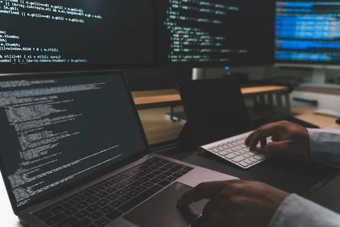 Close up of coding workstation with laptop and multiple screens displaying .. Stock Photos