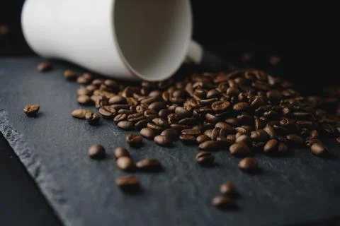 Close up coffee bean spilt from white cup on a rock stone slate. Selected Foc Stock Photos