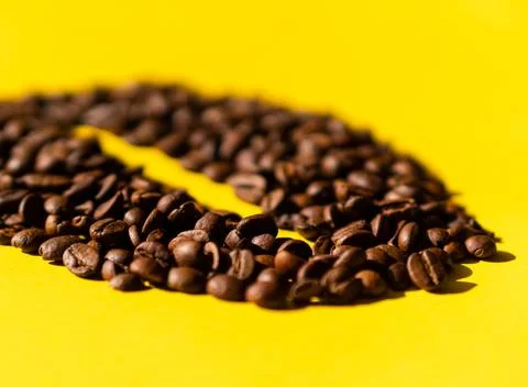 Close-up of coffee beans in the shape of a bean with a yellow background Stock Photos
