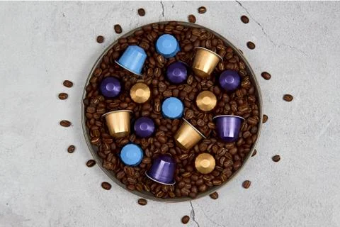 Close up coffee capsules with some roasted grains in plate on concrete Stock Photos