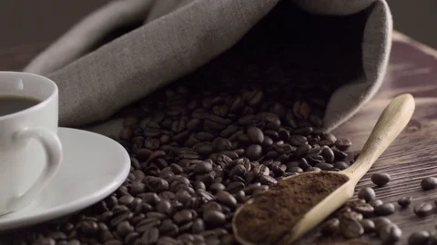 Close-up of coffee cup with roasted coffee beans on wooden background 스톡 동영상 84770998