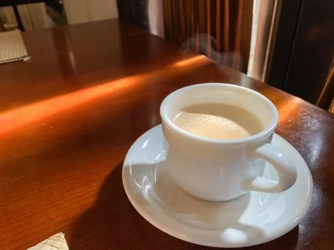 Close up of coffee cup on table at direct sunlight. morning coffee with steam Stock Photos