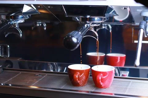 Close-up, coffee cups stand on a grid coffee machine, brewed coffee flows from Stock Photos