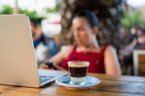 Close up of coffee on table with hands young woman in the background doing Stock Photos