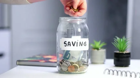 Close-up of coins being added to transparent money jar. Represents traditions Stock Footage 327009945