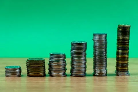 Close-up Of Coins Stack On Wooden Table and green background. Coins stack and Stock Photos