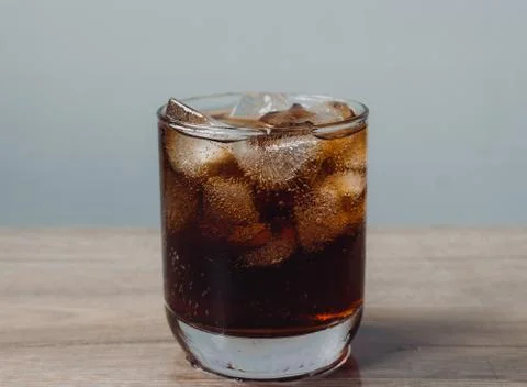 Close up cola and ice cube in clear glass on wooden table Foto stock