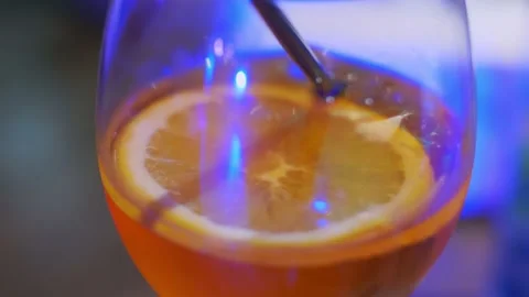 Close up at the cold drink with a piece of orange and a black tube in a glass Stock Footage 151266098