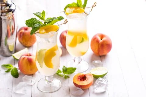 A close up of cold refreshing peach mojitos with a shaker bottle beside. Stock Photos