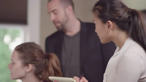 Close up of colleages gathered around a computer in a office and reading charts Vidéo 55350933