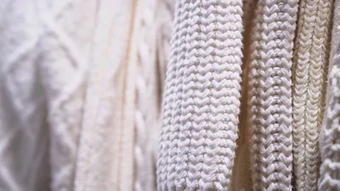 Close-up of a collection of knitted multicolored sweaters hanging on a clothes Stock Footage 189858127