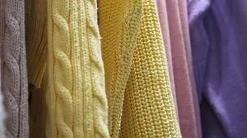 Close-up of a collection of knitted multicolored sweaters hanging on a clothes Stock Footage 189889911