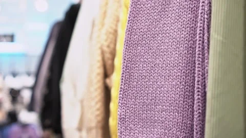 Close-up of a collection of knitted multicolored sweaters hanging on a clothes Stock Footage 191580929