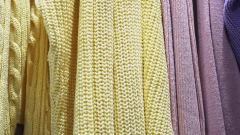 Close-up of a collection of knitted multicolored sweaters hanging on a clothes Stock Footage 193529990