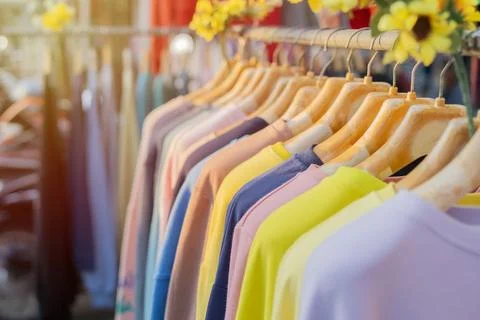 Close up a collection of multi color t-shirts hanging on a wooden clothes h.. Stock Photos
