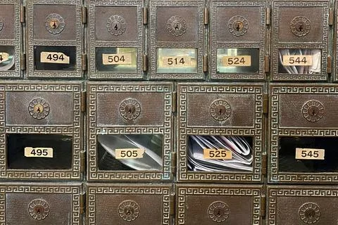 Close-up of a collection of old metal mailboxes with documents Stock Photos