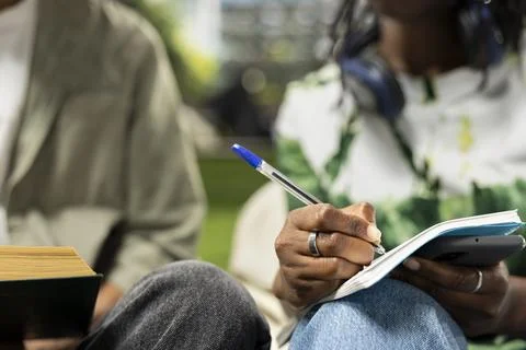 Close-up of college students writing in notebook and studying on campus grass Stock Photos