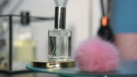 Close-up cologne bottle and pink fluffy ball spinning in slow motion on glass Stock Footage 221864136