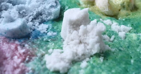 Close-up of colored bath bombs, white, yellow, green, blue, purple, reacting Stock Footage 244054821