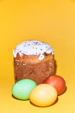 Close-up of colored Easter eggs and a cake on a yellow background. With space to Fotos de archivo
