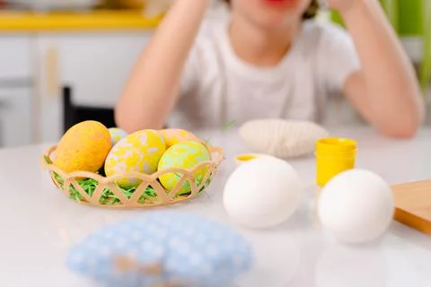 Close-up colored Easter eggs in little basket paints and kids hands on Stock Photos