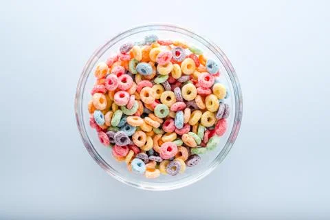 Close up of colored fruit cereal loops in bowl .on a blue background.top view Stock Photos