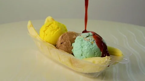 Close-up colored ice cream balls on which pouring sweet cherry topping Stock Footage 91667042