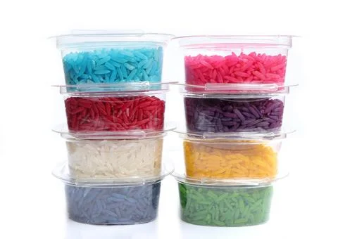 Close up of colored rice in plastic cup on a white background.  Stock Photos