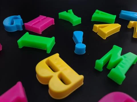 Close up of colorful alphabets on black background perfect for children's edu Stock Photos