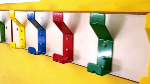 Close up of colorful coat hooks on wall rack in primary school classroom Stock Footage 341069257