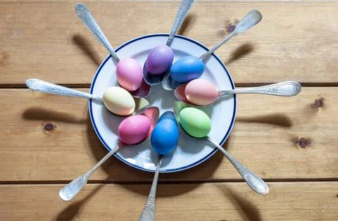 Close-up of colorful Easter eggs in spoons on a wooden background Stock Photos
