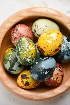 Close up colorful Easter quail eggs in a wooden bowl on a concrete white Stock Photos