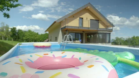 CLOSE UP: Colorful inflatable toys float around empty garden pool in backyard. Stock Footage 159334871