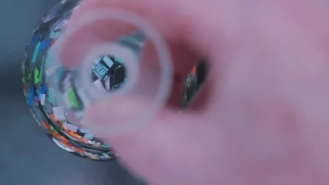 Close up of colorful microplastic pieces spinning in a glass beaker of water in Stock Footage 331322333