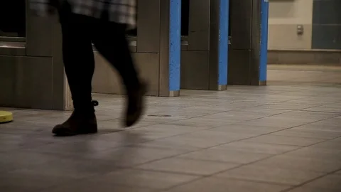 A close-up of commuters feet walking through an entry gate in a Canada Line Stock Footage 100692971