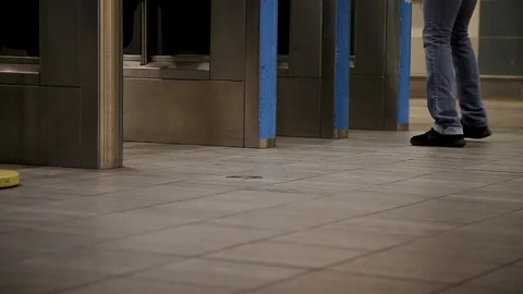 A close-up of commuters feet walking through an entry gate in a Canada Line Stock Footage 100694252