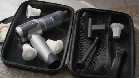 A close-up of a compact cordless vacuum cleaner and accessories in an open case Stock Footage 317772612