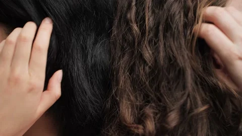 Close up comparison of silky black and curly brown hair being tucked behind ear. Stock Footage 145415647