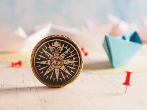 Close up of a compass and location marking with a red pin on sea map. Stock Photos