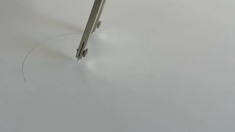 Close up a compass drawing a perfect circle on a smooth white surface. Stock Footage 155959883