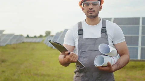 Close up of competent engineer in uniform standing outdoors among solar panels Stock Footage 168520376
