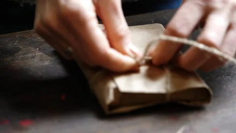 Close-Up Completing Knot on Wrapped Red Leather Wallet on Table Stock Footage 315529021